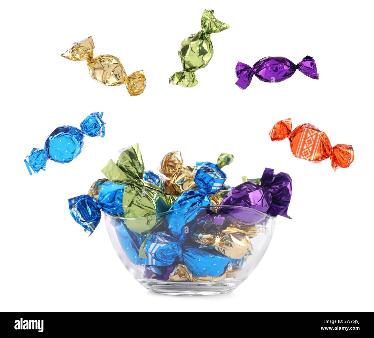 Candies in bright wrappers falling over bowl on white background Stock Photo