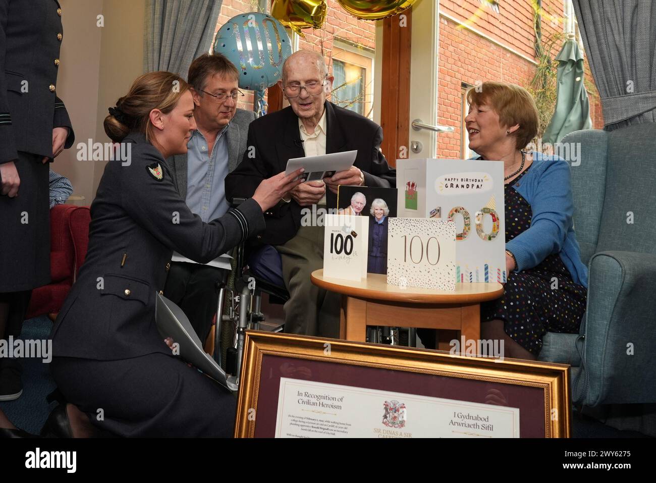 Members of the RAF meet Ian Brignall and Sue Whelan, and their father Ronald Brignall, who was presented with a certificate of civilian heroism, by the Lord Mayor of Cardiff, Councillor Bablin Molik, for saving Cardiff's City Hall from destruction during a German air raid in the Second World War as a 16-year-old, during a party to celebrate his 100th birthday at his care home in Steyning, West Sussex. Picture date: Thursday April 4, 2024. Stock Photo