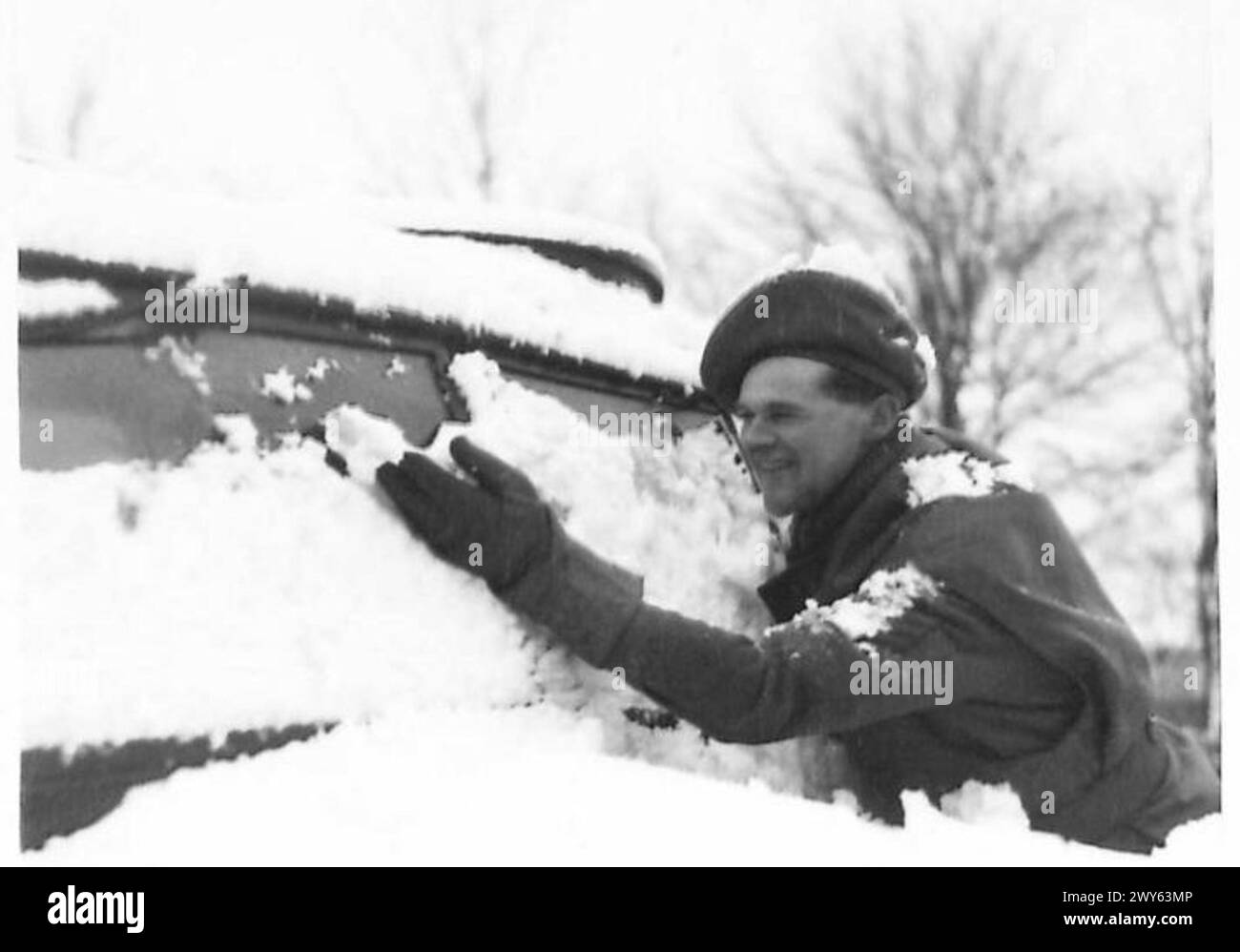 SNOW SCENES IN HOLLAND - Sgt. F.G.Smith, R.A.S.C., of Newark, Notts, pushes the snow off his windscreen. , British Army, 21st Army Group Stock Photo