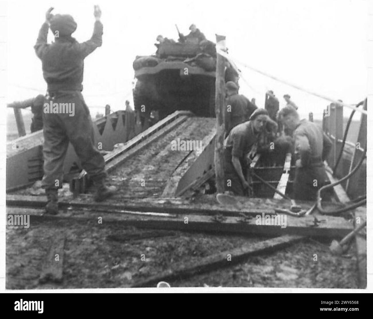 A sapper guides half-track vehicles of the 7th Armoured Division over a ...
