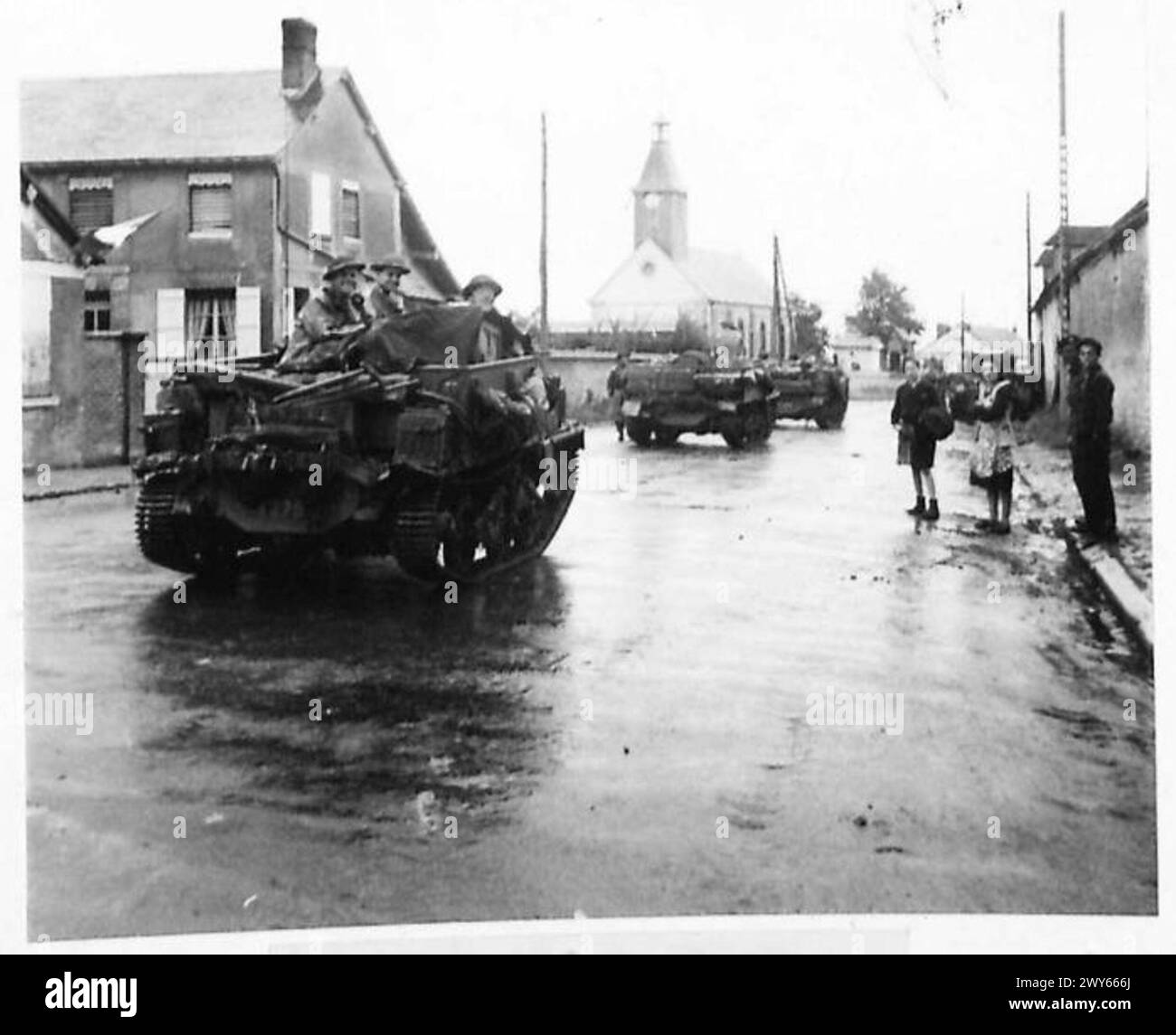 11TH ARMOURED DIVISION ADVANCE - Transport passing through the village of Les Thillers. , British Army, 21st Army Group Stock Photo