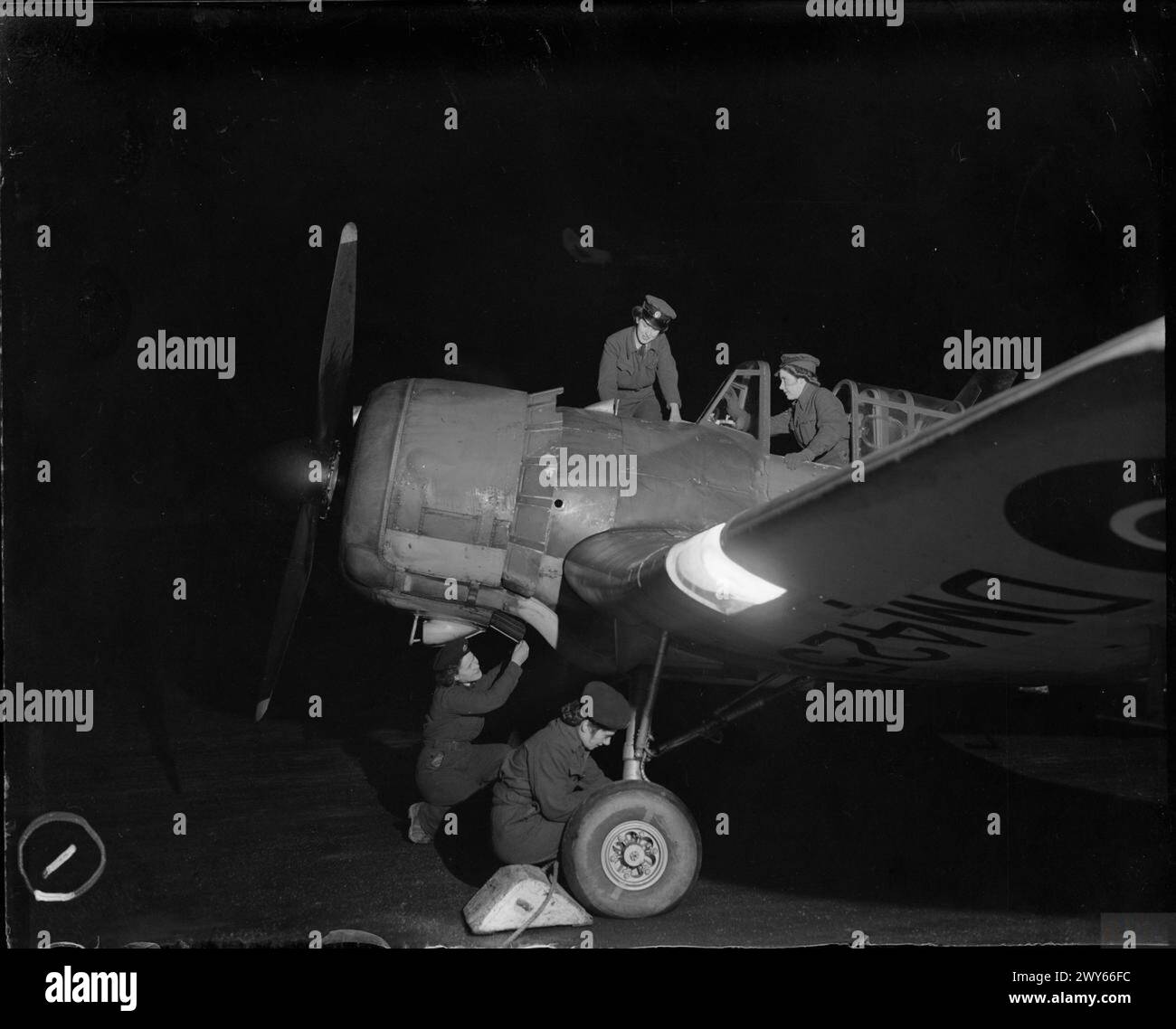 ROYAL AIR FORCE FLYING TRAINING COMMAND, 1940-1945. - WAAF flight mechanics conduct an inter-flight inspection on Miles Master Mark II, DM425, of No. 9 (Pilots) Advanced Flying Unit at night at Errol, Perthshire. They are, in the cockpit, Corporal H Shaw; on the fuselage, Leading Aircraftwoman M Agnew; on the ground (left) Aircraftwoman M H Arnott, and Aircraftwoman C W Fraser; all from Glasgow. , Royal Air Force, Wing, 901, Royal Air Force, Women's Auxiliary Air Force Stock Photo