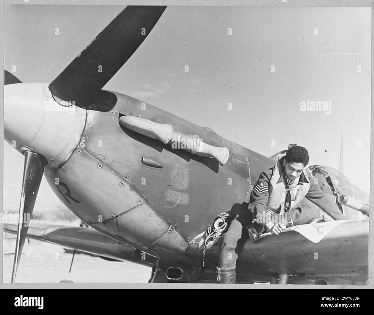 MEN AND 'PLANES OF THE BOMBAY SQUADRON 'STRAFE'ENEMY-OCCUPIED TERRITORY. - Spitfires and men of the Bombay Squadron - they have taken part in Fighter Command sorties over enemy-occupied territory. Picture (issued 1943) shows - Flight Sergeant C.A. Joseph of San Fernando, Trinidad, studying the map before taking off. , Royal Air Force Stock Photo