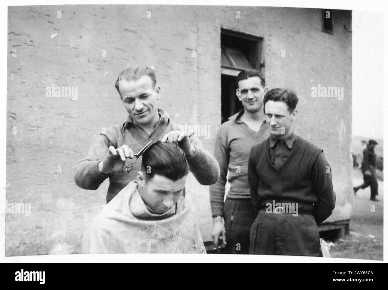 THE LIBERATION OF STALAG 7A, MOOSBURG, GERMANY - The barber is Gunner Gerald Shirley, Royal Artillery aged 15 years; 7 years in the army, prisoner of war 5 years. He was captured at St.Valery in France, 12th June 1940 and had been a P.O.W. in France, Italy and Germany. In all the camps and Stalags during his captivity he had been employed as a hairdreesser. He escaped twice to Spain but was refused entry. Gunner Shirley is not married and his home address is 5 Tregarne Terrace, St.Austel, Cornwall. , British Army, 21st Army Group Stock Photo