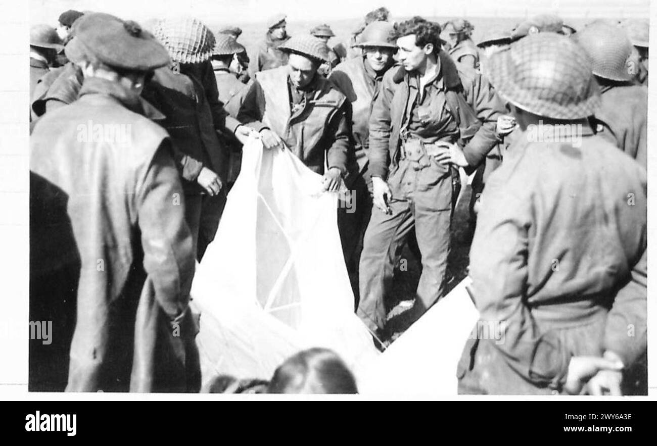 CROSSING THE RHINE - An American airman whose plane was hit and caught fire baled out over our lines. He is showing men of the Gordon Highlanders his parachute. , British Army, 21st Army Group Stock Photo