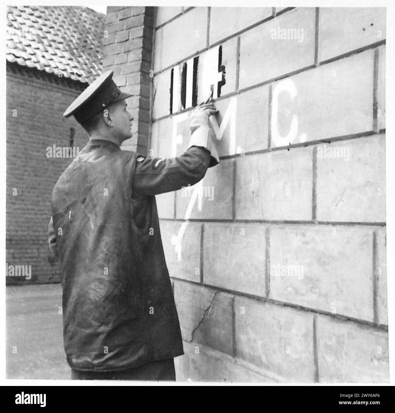 STEIN CORPS OF MILITARY POLICE AT WORK - L/Cpl Parsons altering a sign painted on a wall. L/Cpl W.A. Parsons: Married. Lives at 57 Westcourt Road, Worthing, Sussex. Before the War, a Costletizer (anti-rust proofing of motor-bikes), working for Associated Motorcycles Ltd, Plumstead. Joined the Army in May 1939. Was in BEF and landed in France D/15. Hobby - Cycling. , British Army, 21st Army Group Stock Photo