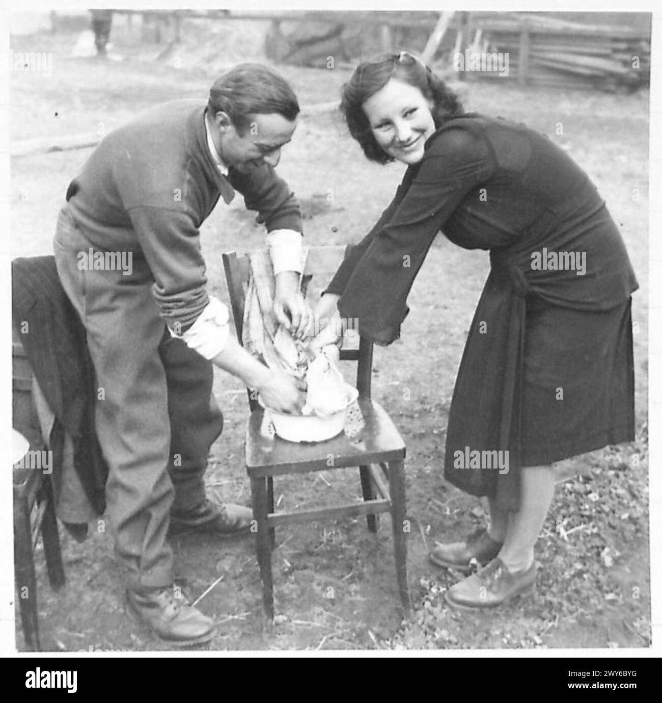 BRITISH MILITARY GOVERNMENT CENTRE FOR LIBERATED P.O.Ws. - Antoine Coletta, a released French P.O.W., helps his finacee, a Russian girl, to do some washing on arrival at the Centre. They met while working as forced labourers on a farm. The girl's name is Miss Lena Lubikiski. , British Army, 21st Army Group Stock Photo