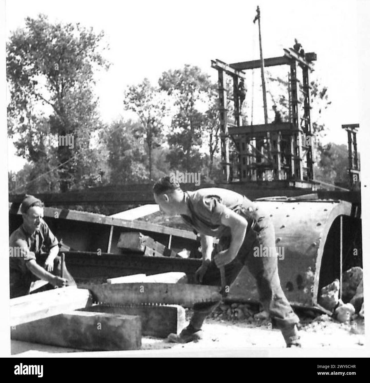 CONSTRUCTION OF NEW RAILWAY BRIDGE OVER RIVER ORNE - Royal Engineers sawing baulks of timber for use in the construction of the central pier. , British Army, 21st Army Group Stock Photo