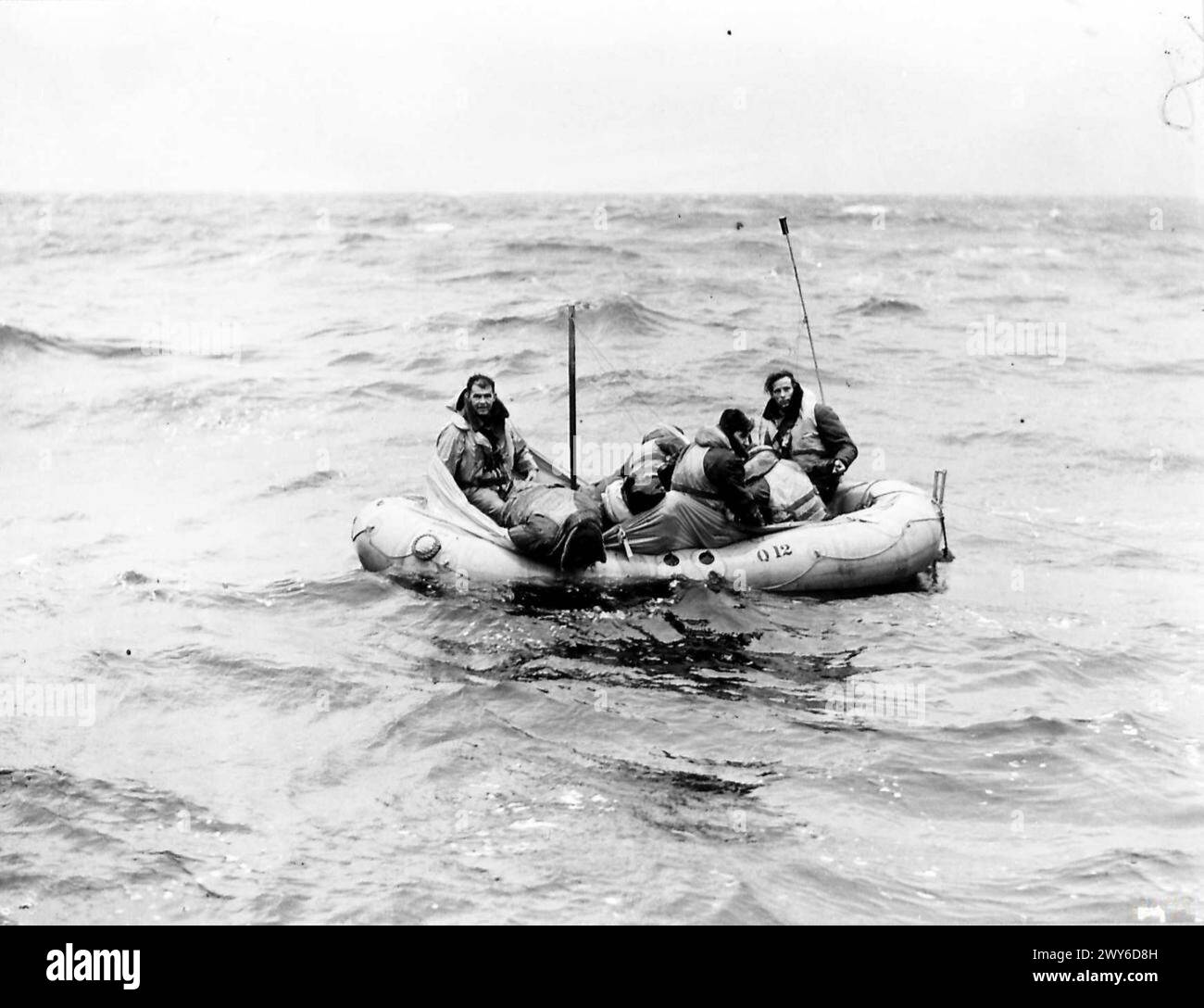 Five men navigate a Q-type dinghy through heavy seas, with most crew members distressed and seasick during the passage. Stock Photo