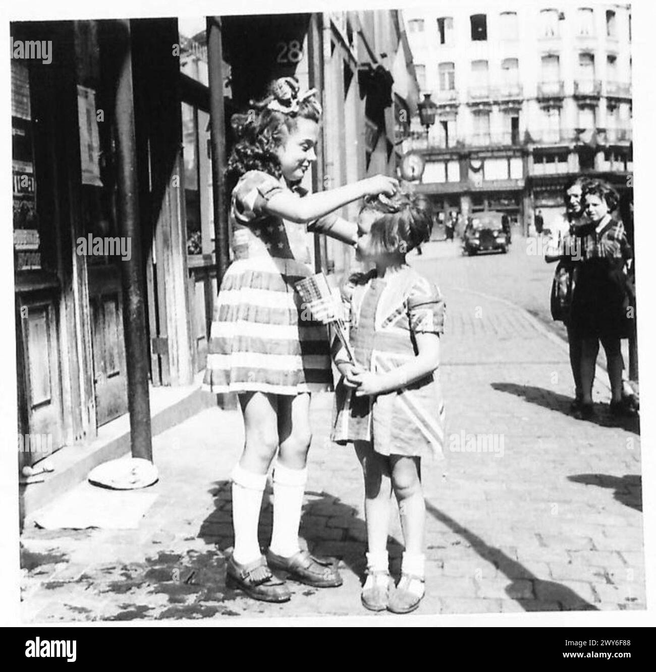 PEACE CELEBRATIONS IN BRUSSELS - Two little girls wearing dresses made from the Union Jack and Stars & Stripes. [Left] Elizabeth aged 10 1/2 years wearing the Stars and Stripes, and [right] Francine aged 4 1/2 years wearing the Union Jack. , British Army, 21st Army Group Stock Photo