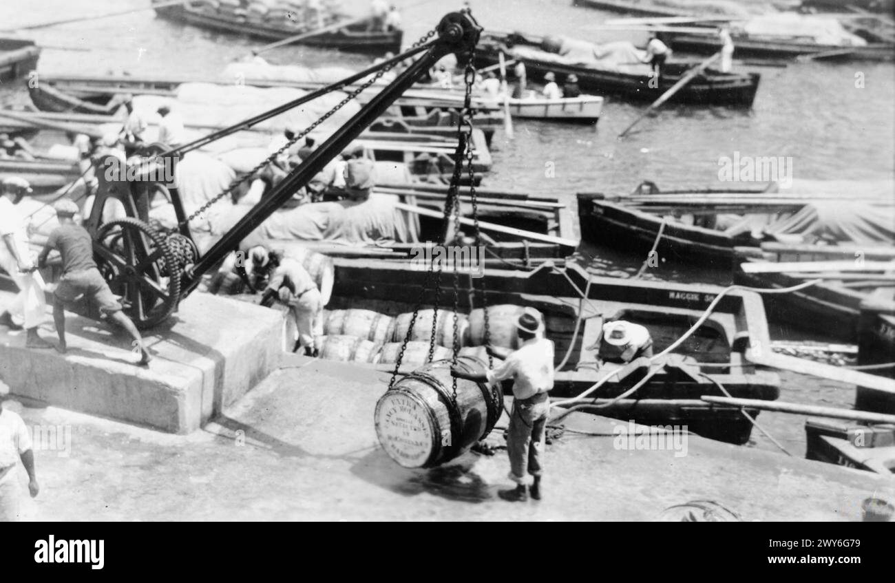 BARBADOS SUGAR INDUSTRY, C. 19 MARCH 1945 - Picture taken in Barbados, most easterly island of the British West Indies, showing the production of sugar, the island's staple industry. West Indians provide the labour. Picture shows:- Puncheons of molasses being loaded into a lighter ready for shipment abroad. A black and white copy negative , Stock Photo