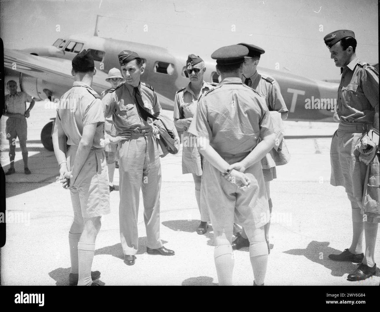 ROYAL AIR FORCE OPERATIONS IN THE MIDDLE EAST AND NORTH AFRICA, 1939-1943. - The new Air Officer Commanding-in-Chief, Middle East Command, Air Marshal A W Tedder (second from left in foreground group), arrives at Lydda, Palestine, to discuss operations in Iraq and Syria with his senior officers. On Tedder's left, wearing sunglasses, is Air Commodore (although still wearing Group Captain's badges of rank) L O Brown, recently appointed Air Officer Commanding, Palestine and Trans-Jordan. At far right stands Squadron Leader G Bray, Tedder's Personal Assistant Staff Officer. Tedder's aircraft, behi Stock Photo