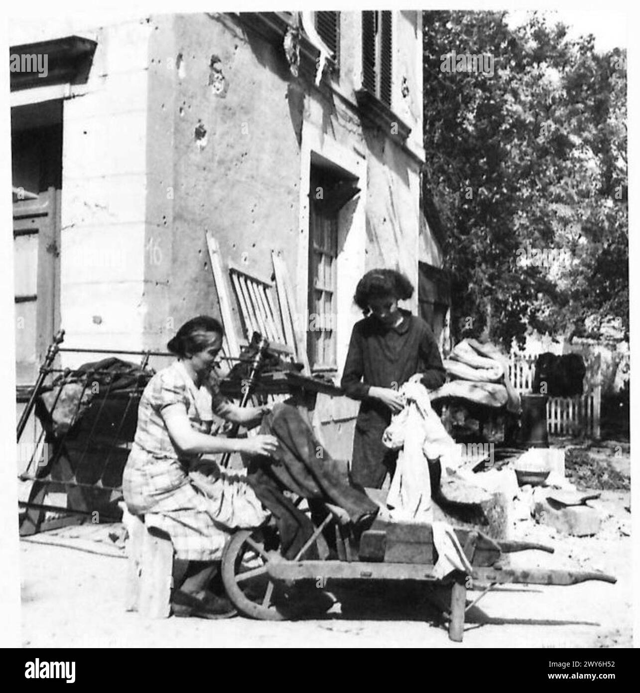 A FRENCH FAMILY RETURN TO THEIR SHELL TORN VILLAGE - Madame Le Du and Mari-Anne sort out the salvaged clothes as they are brought from their former home to their new home. , British Army, 21st Army Group Stock Photo