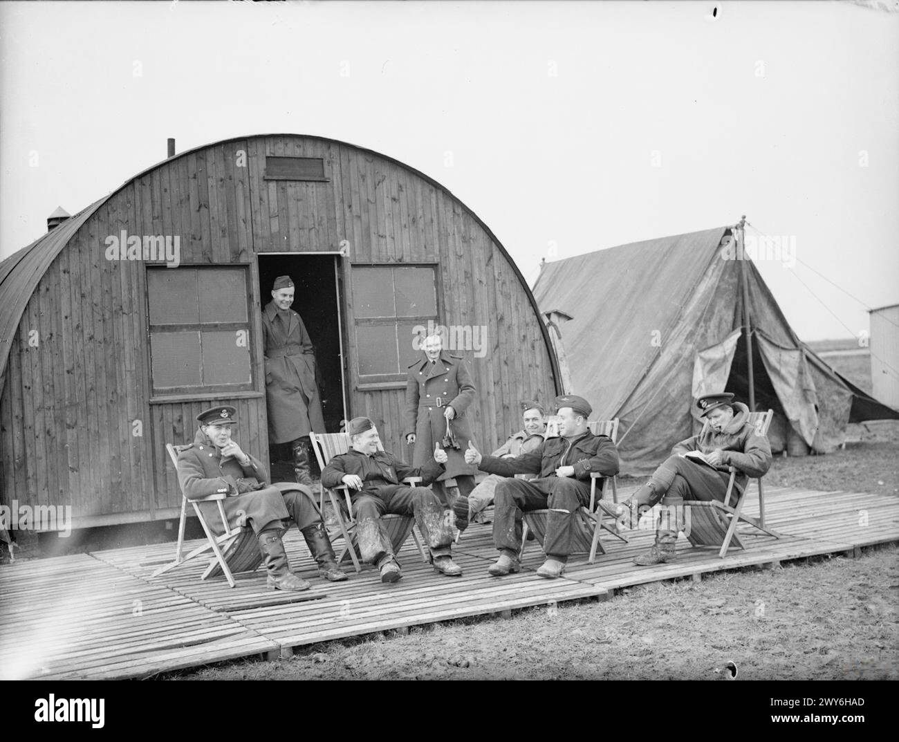 ROYAL AIR FORCE: FRANCE, 1939-1940. - Pilots of No. 607 Squadron RAF relax outside their crew room at Vitry-en-Artois. Those identified include Pilot Officer P L Parrott (first left), Flying Officer W F Blackadder (second right) and Flying Officer W E Gore (first right). Blackadder and the officer with whom he is exchanging a 'thumbs up' are still dressed in their pre-war Royal Auxiliary Air Force blue overalls with the Squadron badge emblazoned on the front left pockets. , Royal Air Force, Maintenance Unit, 67 Stock Photo