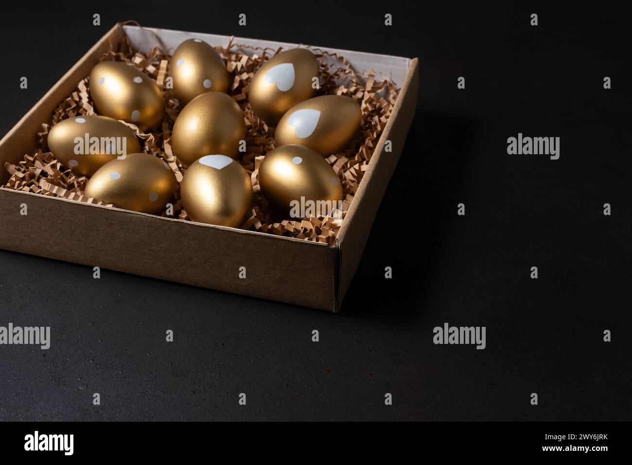 Gold eggs in paper box on black background. Stock Photo