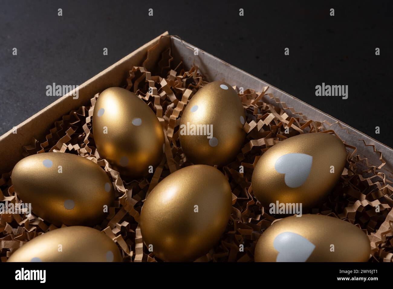 Gold eggs in paper box on black background. Stock Photo