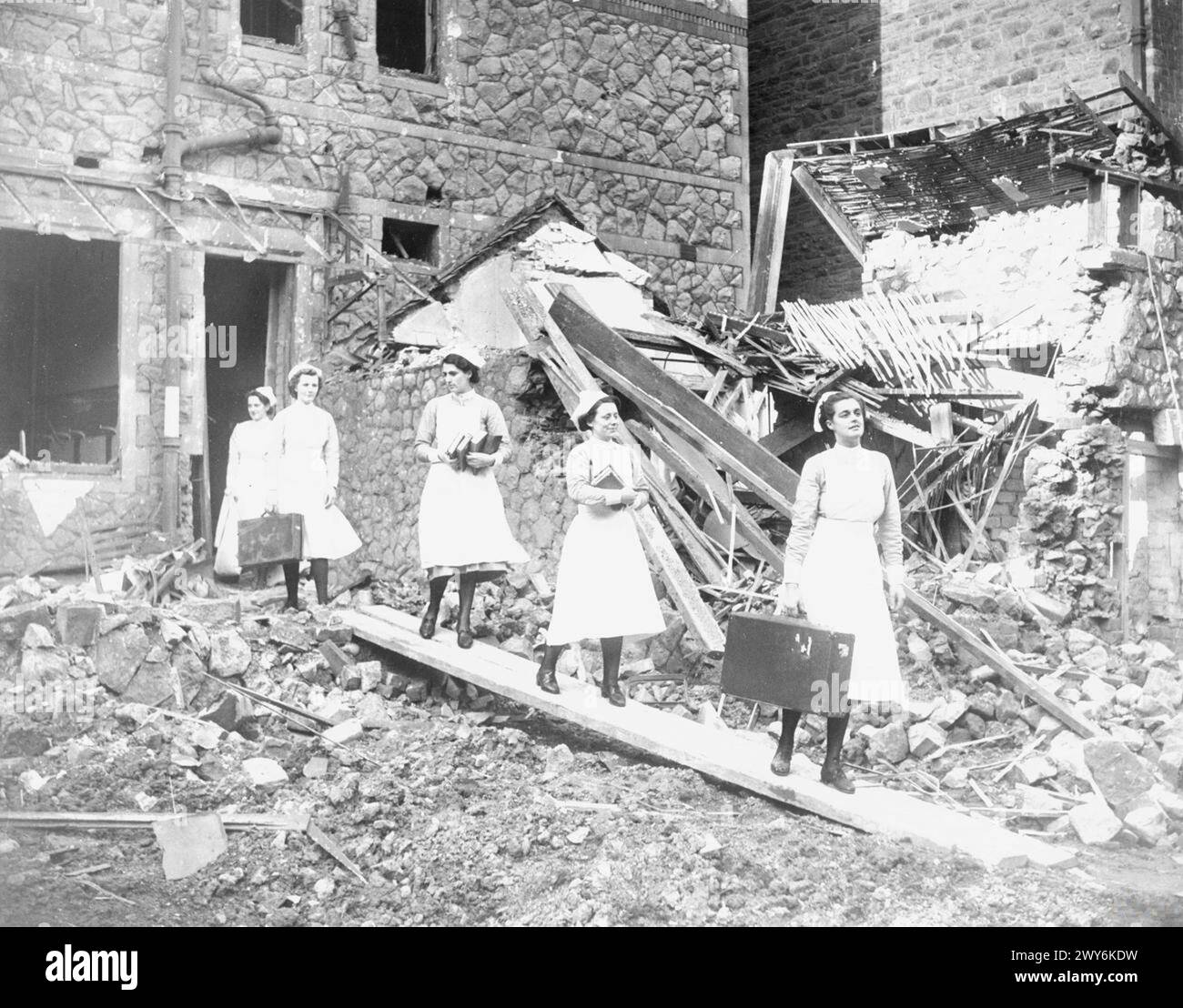 Nurses are leaving the damaged nurses' home of the Royal Infirmary in Cardiff after a German air raid in 1941, carrying salvaged personal belongings. Stock Photo