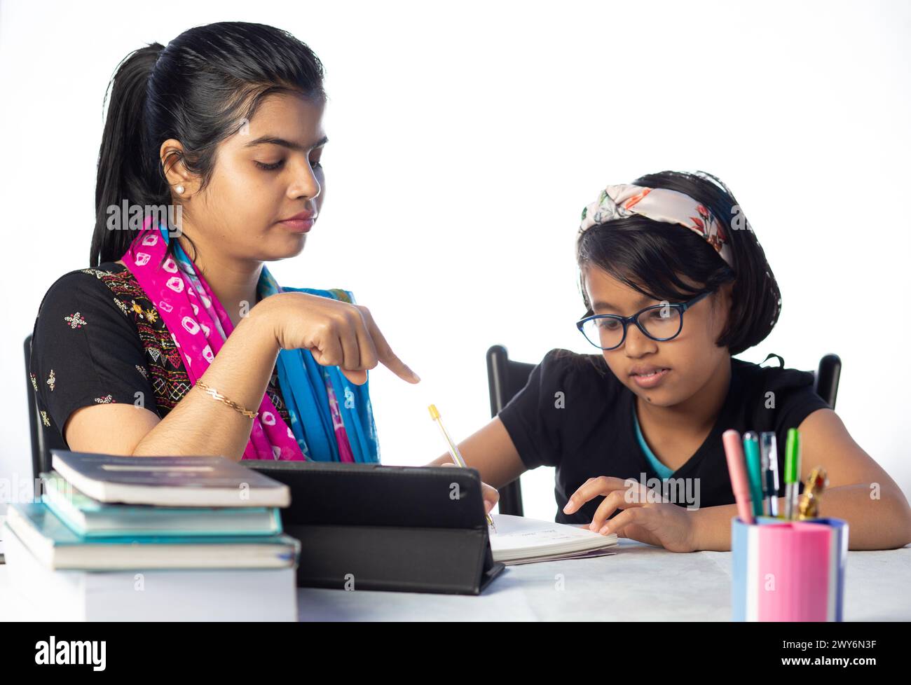 An Indian girl student studying with tablet besides her mother, teacher ...