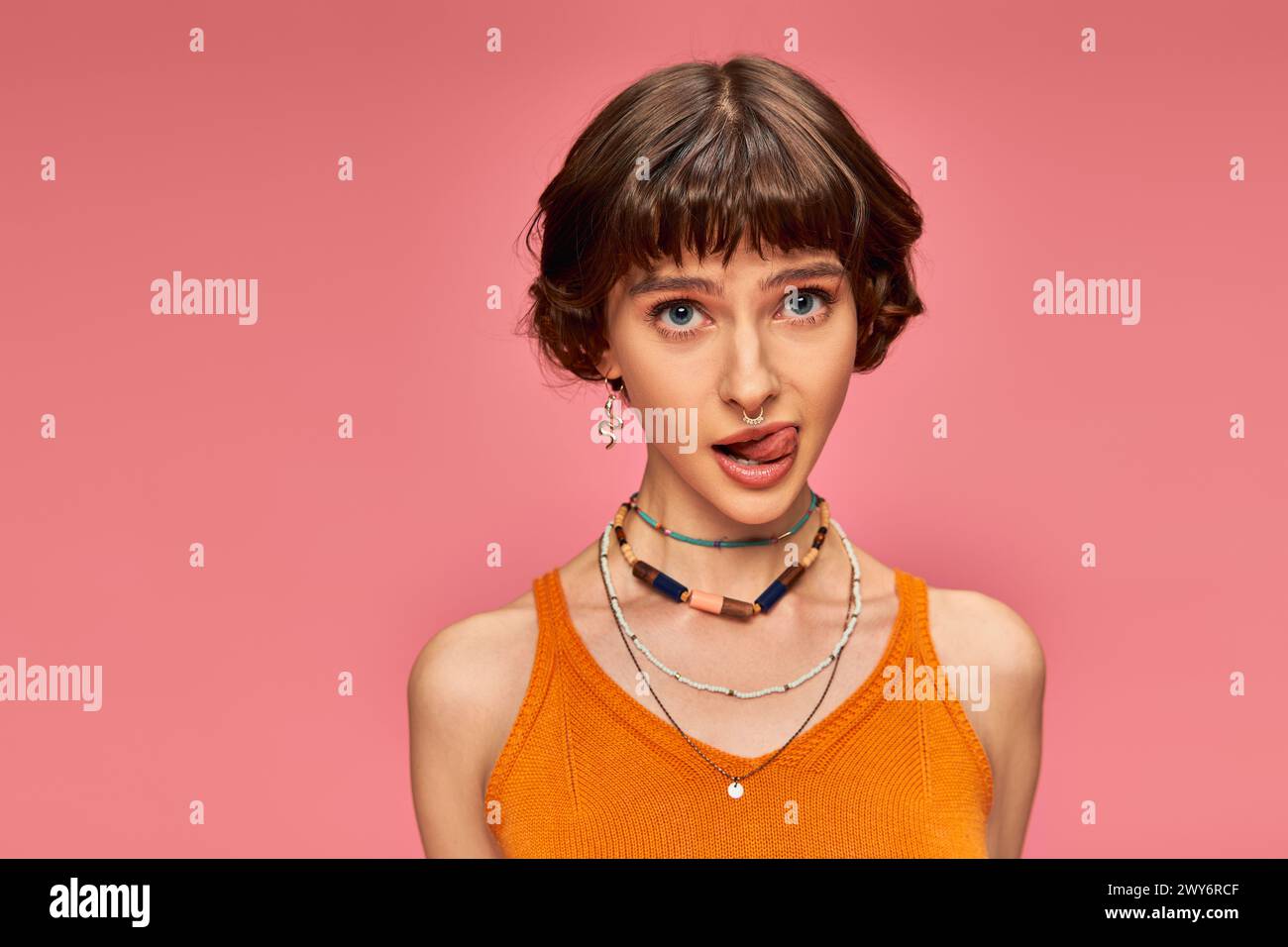 cheeky playful girl in 20s with short brunette hair sticking tongue out