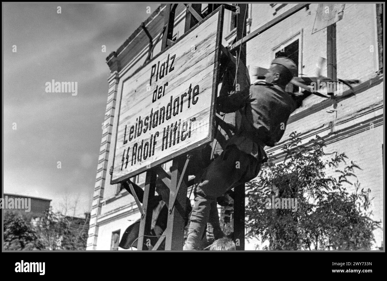 WW2 USSR/Nazi Germany KHARKOV 1943 Red Army soldier destroys a Nazi German sign on Dzerzhinsky Square in liberated Kharkov. During the German occupation from 1942 it was called “German Army Square”. From the end of March to August 23, 1943, it was called “Leibstandarte SS Square” after the name of the 1st SS Panzer Division “Leibstandarte SS Adolf Hitler” that captured the city for the second time in the third battle for Kharkov. Kharkiv also known as Kharkov the second-largest city in Ukraine Stock Photo