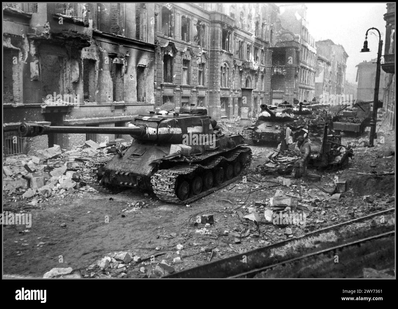 TANKS WW2 Nazi Berlin falling to Russian Soviet USSR overwhelming force as a column of Soviet heavy tanks IS-2's on a heavily bombed and shell damaged street in central Nazi Berlin Germany 1945 The IS-2 is a Soviet heavy tank, the second of the IS tank series named after the Soviet leader Joseph Stalin. It was developed and saw combat during World War II Stock Photo