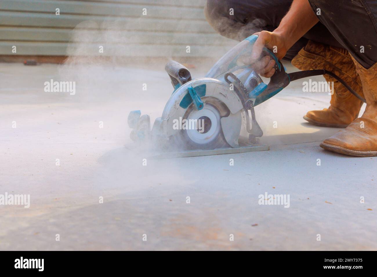 Construction worker uses cutting machine grinder to cut concrete