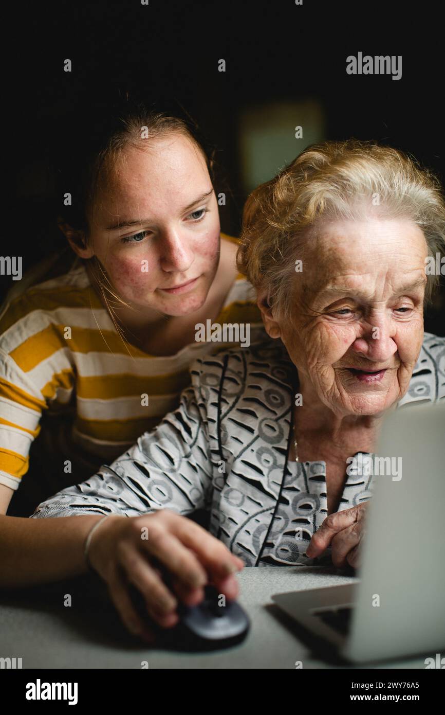 A girl teaches her grandmother how to use the computer. Stock Photo