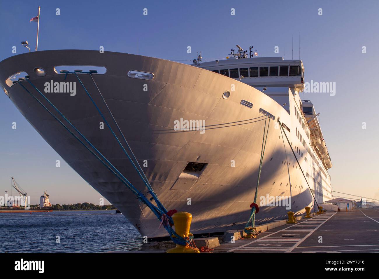 A grand cruise ship moored at the harbor, bathed in sunrise. Stock Photo