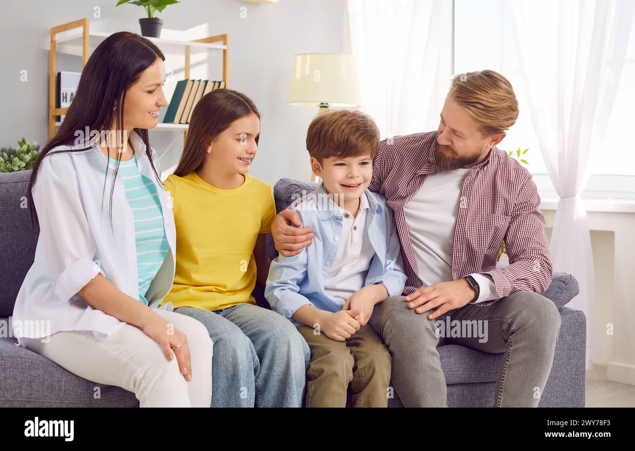 Smiling young happy family sitting on the sofa at home spending weekend together Stock Photo