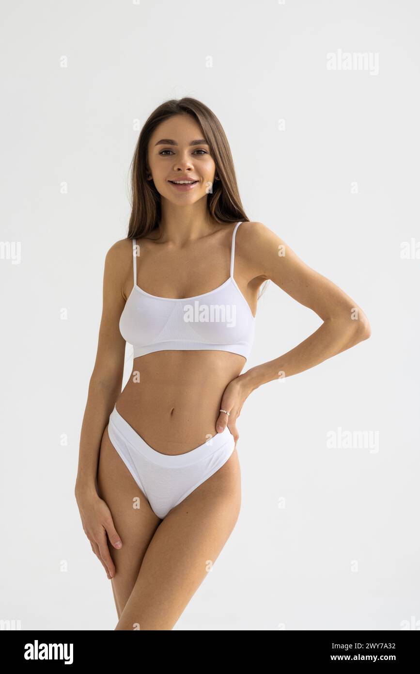 Close up shot of a fit woman in lingerie isolated on white background. Slim attractive female with flat belly in white underwear posing. Copy space fo Stock Photo