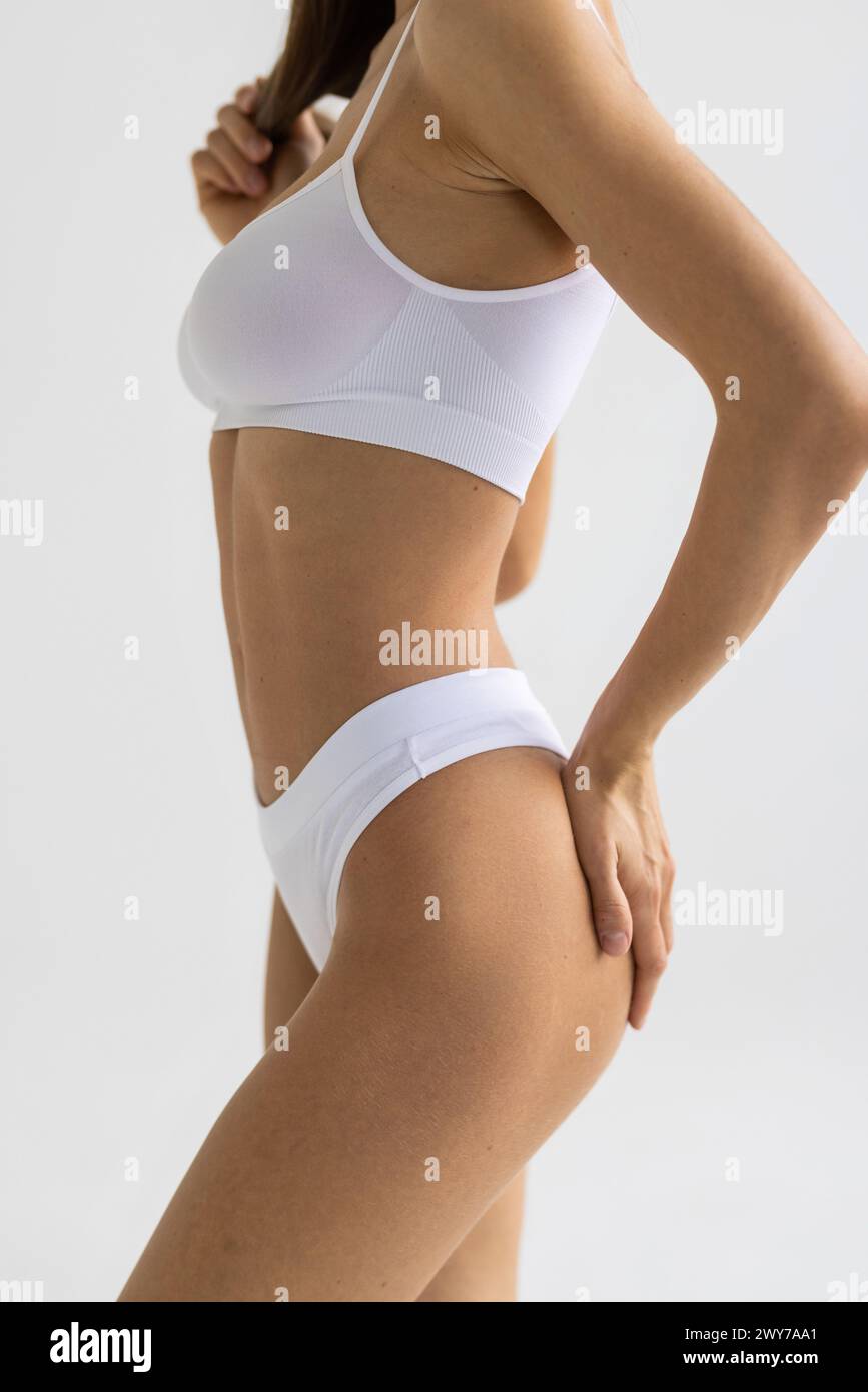 Tanned woman in top form, perfect body shape. Parts of woman body in underwear, studio shoot. Stock Photo