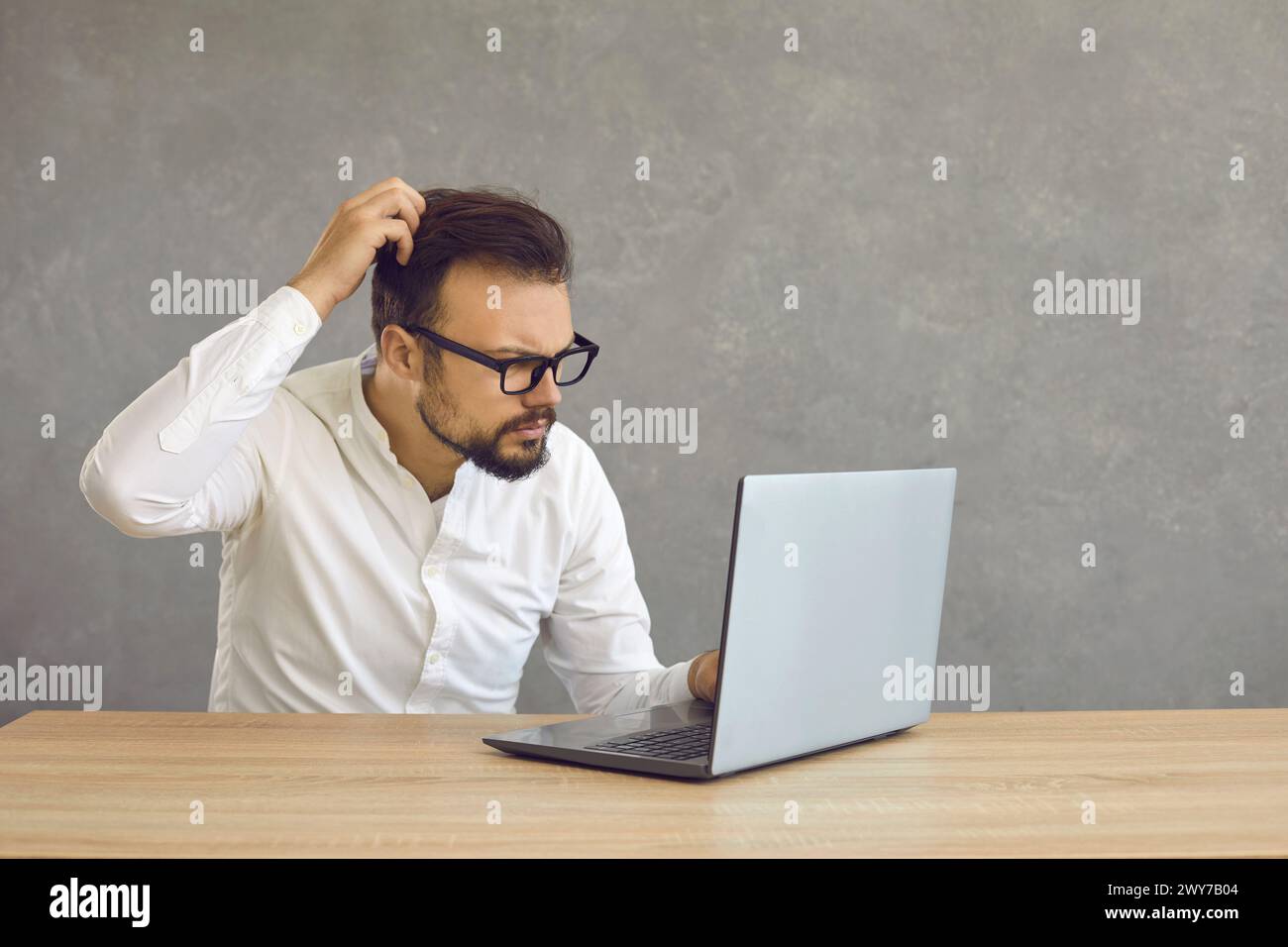 Young man having computer problem and looking at screen of his laptop ...