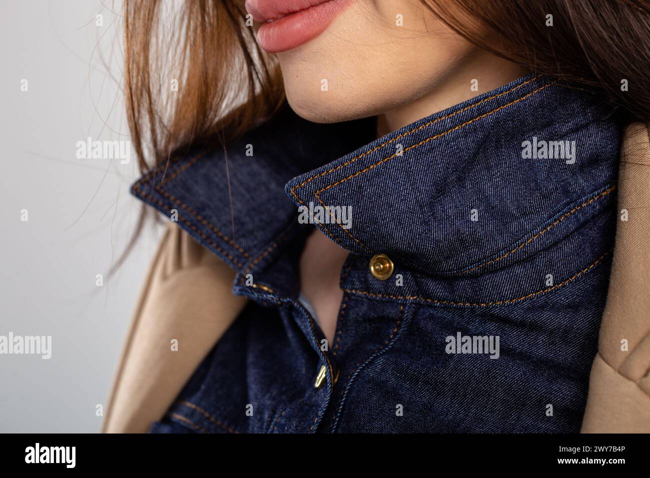 Close-up of a blue denim shirt collar with a brown corduroy jacket lapel. Shirt is buttoned up, collar turned up, and jacket open. Stock Photo