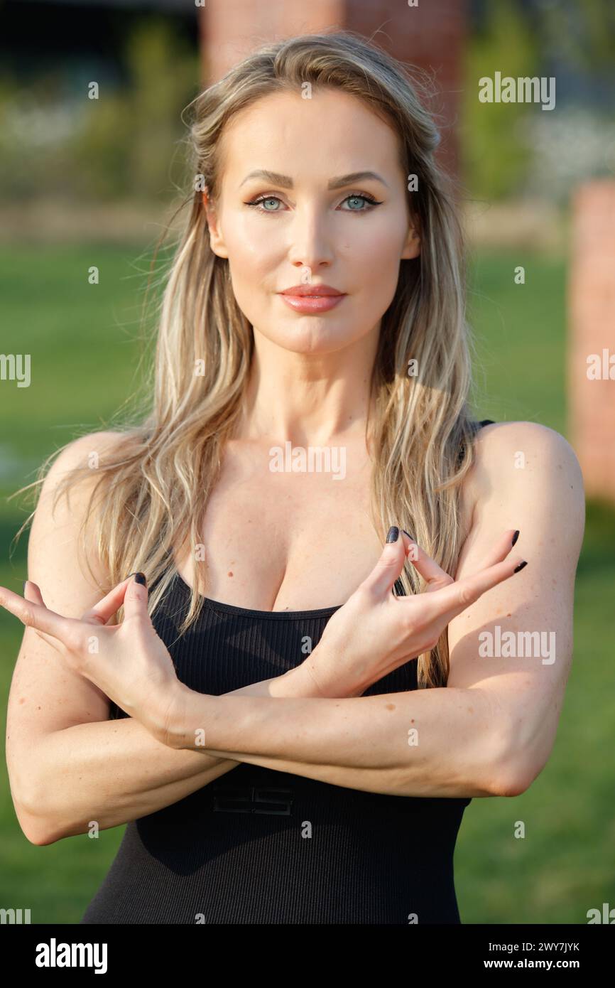 a beautiful female blonde model and yoga teacher, doing yoga in the CityLife park, in front of the Coloris sculpture, CityLife, Milan, Italy Stock Photo