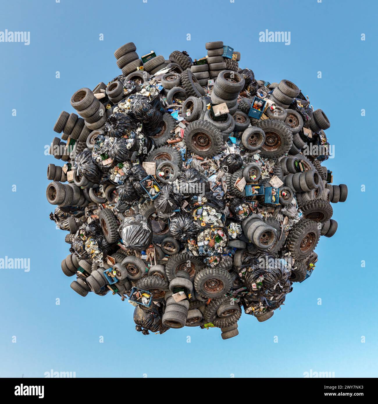 3D rendering of little planet completely covered by old tires and domestic trash over blue sky Stock Photo
