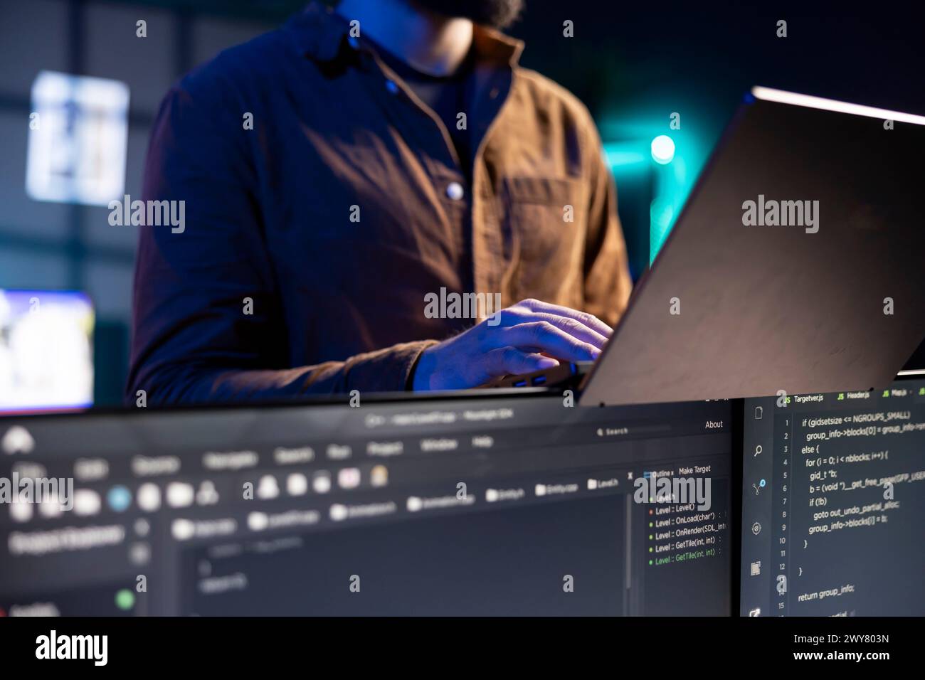 Freelancing IT administrator working from home using laptop, testing and deploying programs. Software technician checking code displayed on computer displays, standing in apartment, close up shot Stock Photo