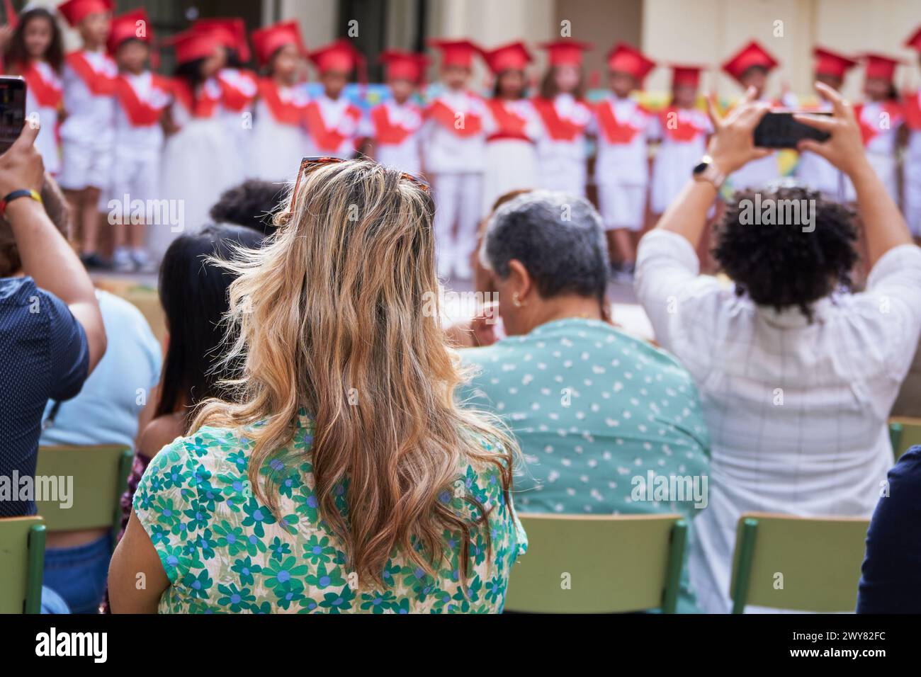 Proud multiethnic families attending children graduation from pre primary to elementary school Stock Photo
