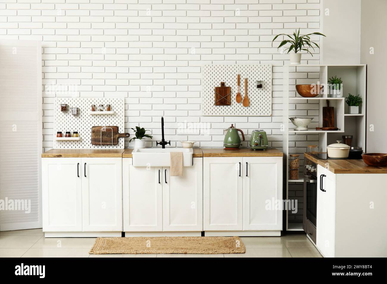 Stylish light kitchen with pegboards and kitchenware Stock Photo