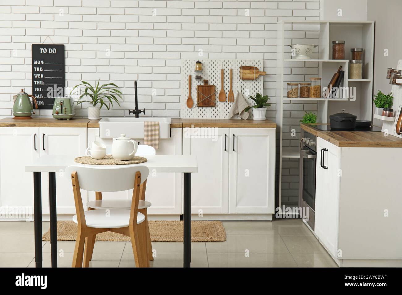 Stylish light kitchen with pegboard and modern dining table Stock Photo ...