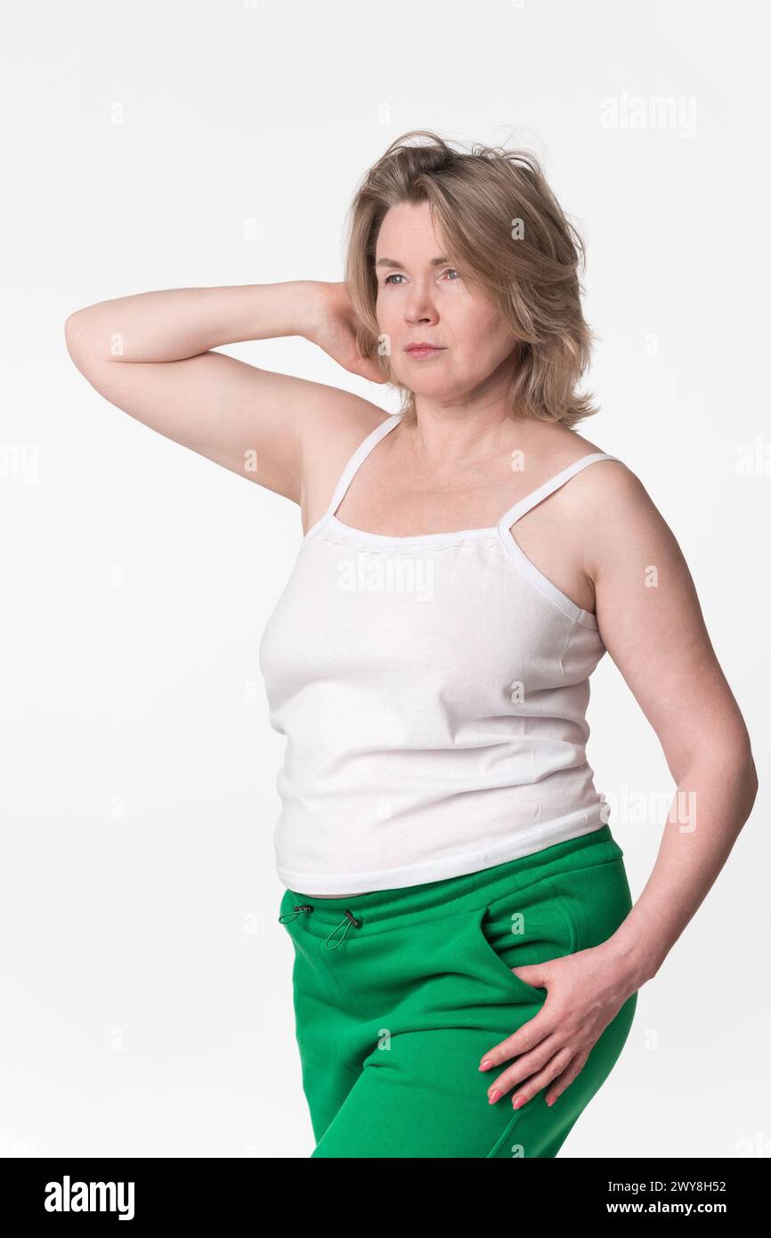 chubby mature Portrait of chubby mature adult blonde woman Generation X model wearing  cotton camisole and green jogging pants. Comely woman with one hand raised  beh Stock Photo - Alamy