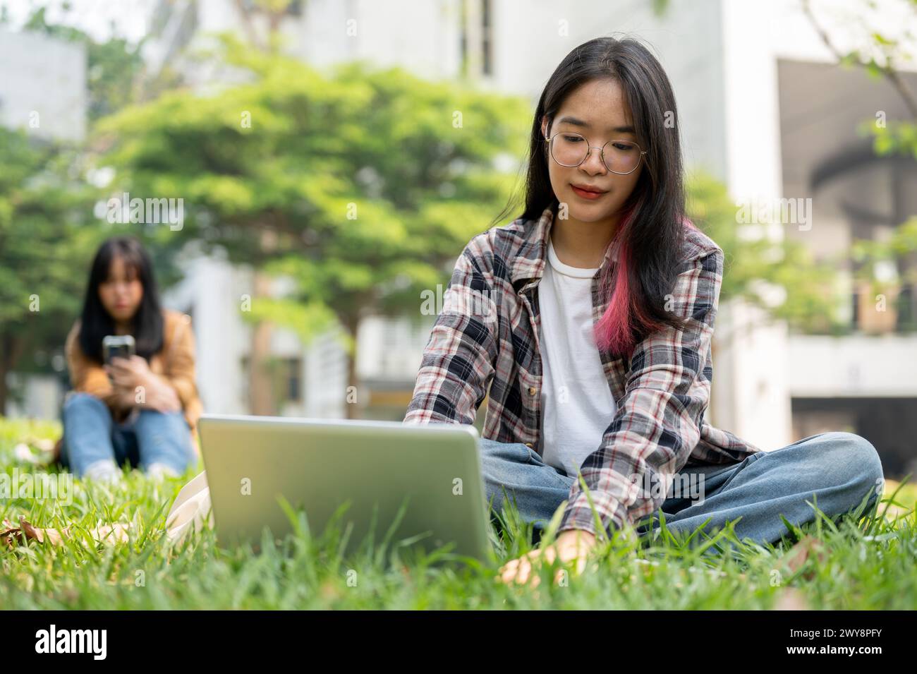 A focused young Asian female college student is working on her homework ...