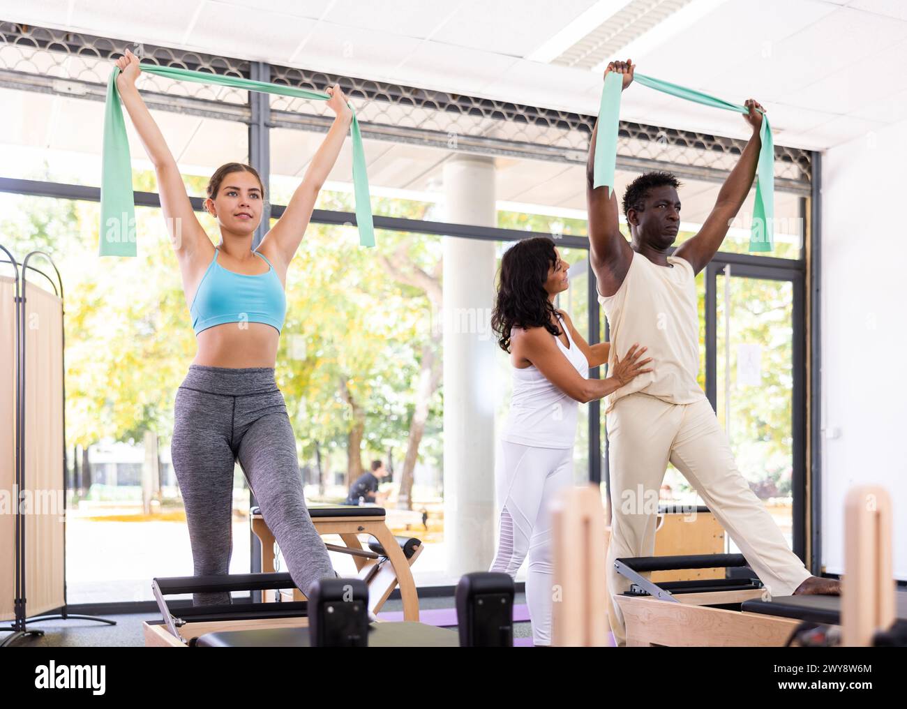 Multiethnic group of people training pilates in gym with trainer Stock Photo