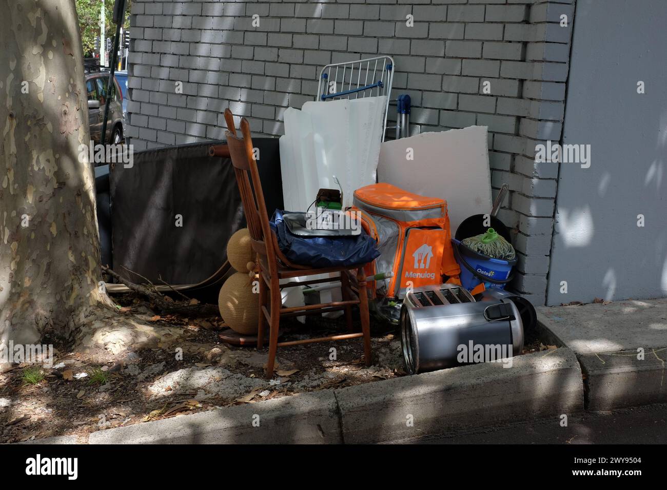 Chair, bin, couch, cleaning and kitchenware, dumped household goods on the footpath, housing stress on the streets of Darlinghurst, Sydney Stock Photo