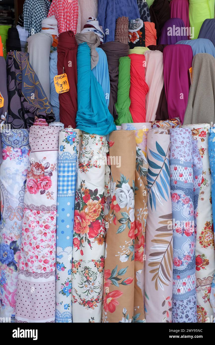 Fabric displayed in rolls of bright colours and rolls of floral patterns in a dressmaking store