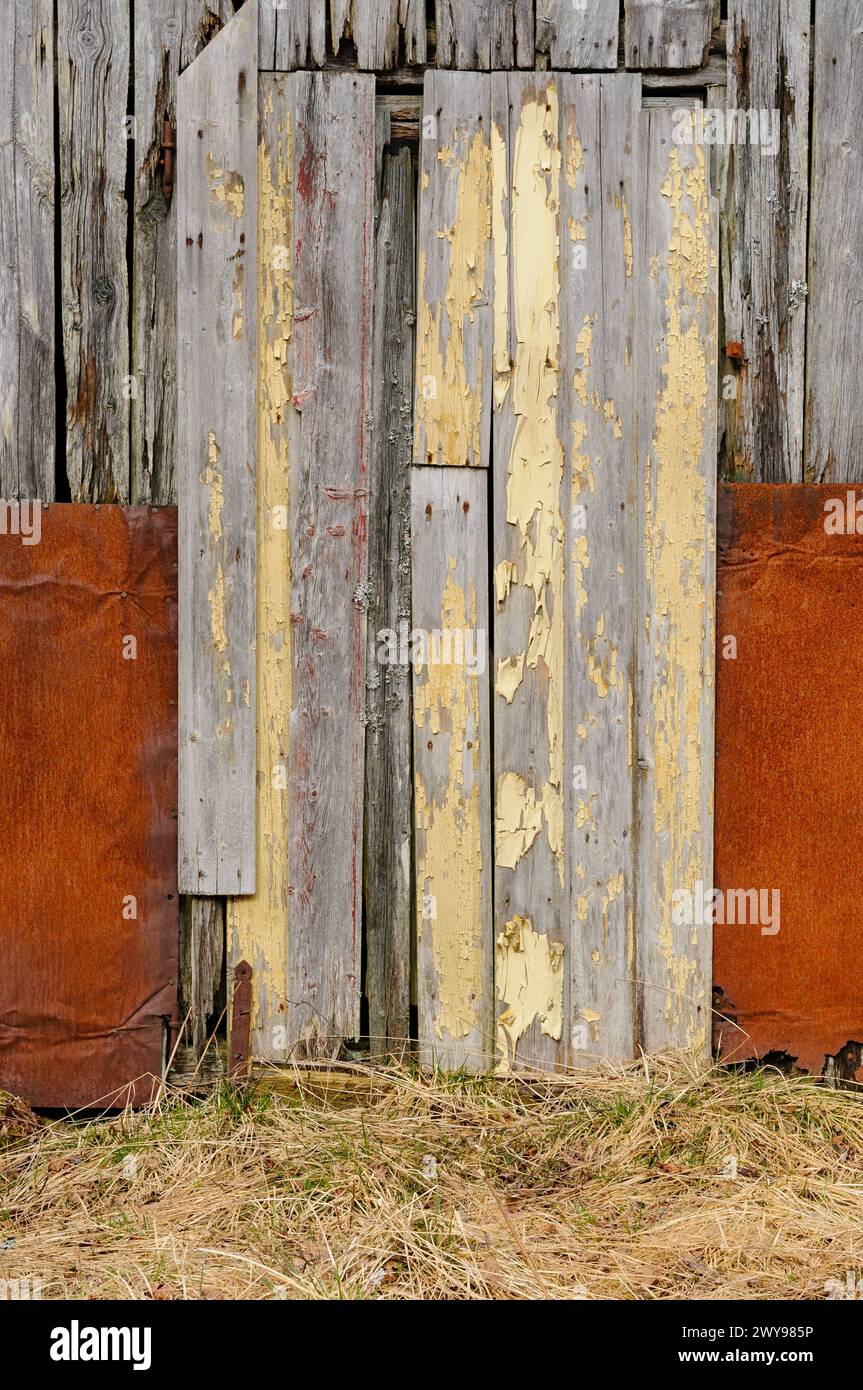 A worn wooden door with flaking yellow paint is framed by rusted metal