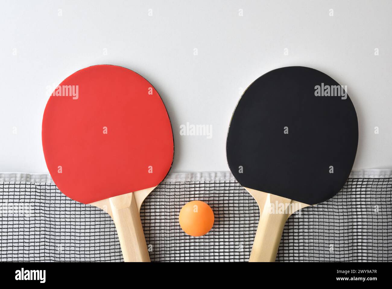 Background with set of table tennis paddles; net and orange ball isolated on white table. Top view. Stock Photo