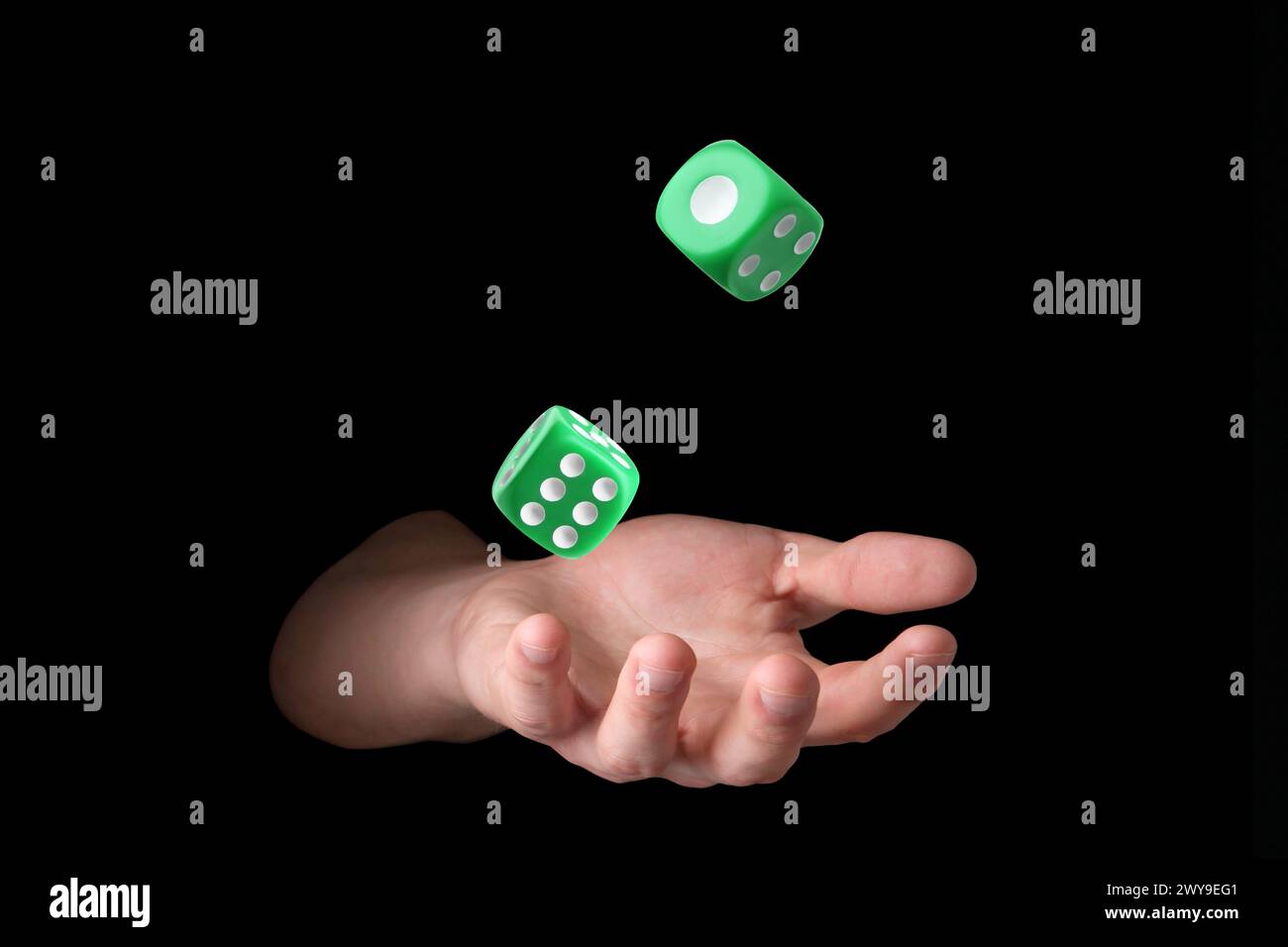 Man throwing green dice on black background, closeup Stock Photo