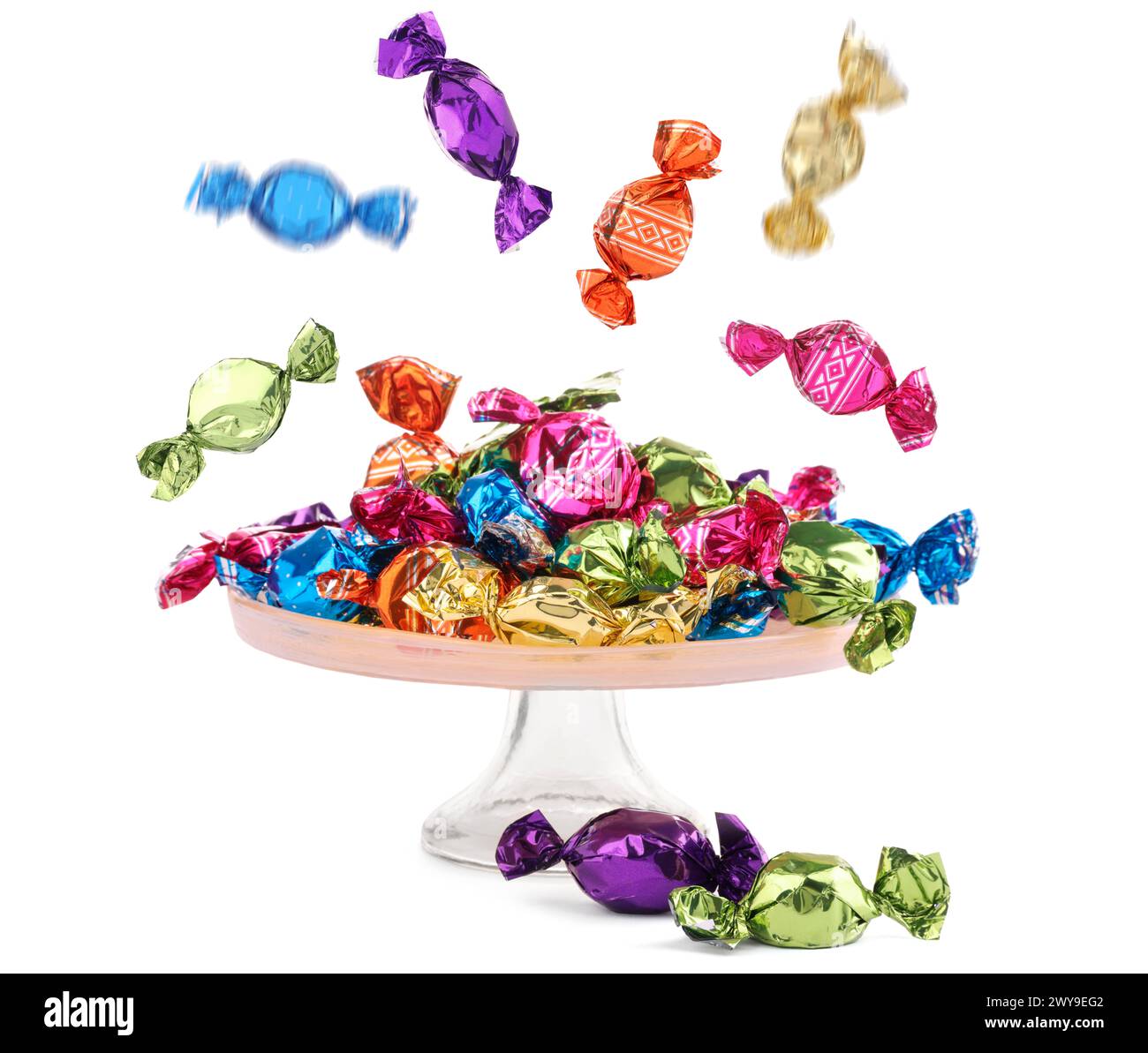 Candies in bright wrappers falling over stand on white background Stock Photo