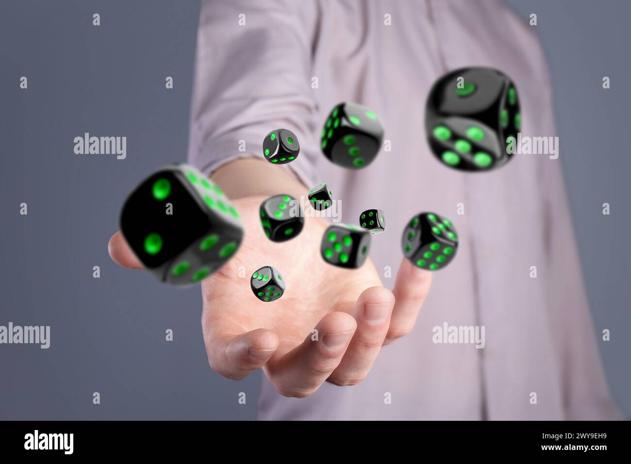 Man throwing black dice on grey background, closeup Stock Photo