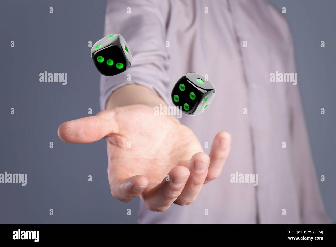 Man throwing black dice on grey background, closeup Stock Photo